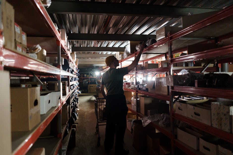 Worker manually stocking shelves in a warehouse, illustrating traditional inventory management challenges.