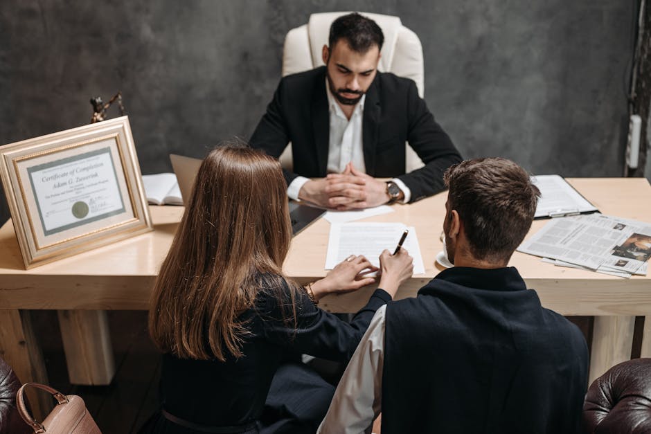 A lawyer consults with a couple signing legal documents at a desk, representing a manual legal review.