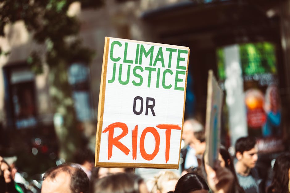 Protest sign 'CLIMATE JUSTICE OR RIOT' at a climate rally, urging action for a sustainable future.