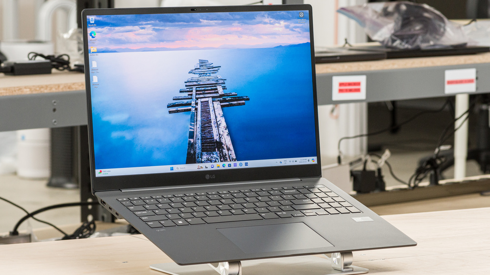 LG Gram Pro 16 (2024) laptop open on a silver stand, displaying Windows 11 desktop with a scenic pier wallpaper.