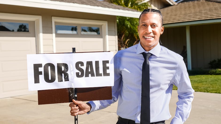 Smiling real estate agent holding a 'FOR SALE' sign in front of a house, representing investment opportunities.