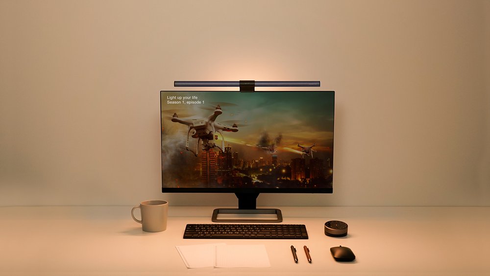 BenQ ScreenBar Halo monitor light illuminates a modern desk with a display showing drones, keyboard, mouse, and controller.