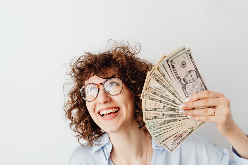 Happy woman in glasses holding a fan of US dollar bills, symbolizing financial success from AI passive income streams.