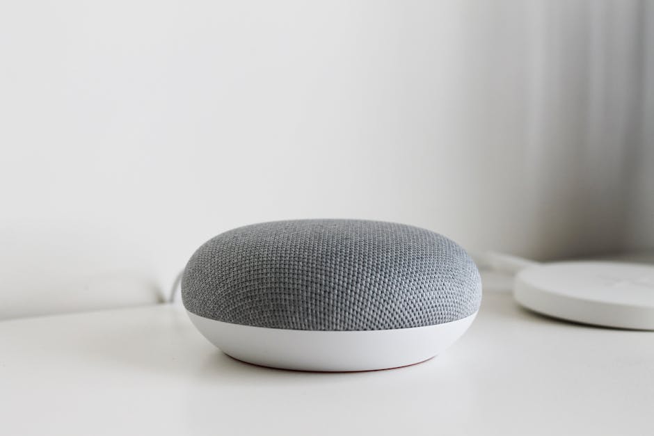 Gray smart speaker on a white surface, representing voice-first AI interfaces for educational applications.