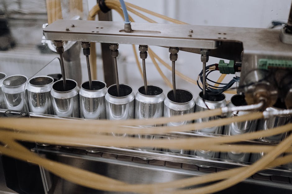 Close-up of an industrial machine automating the filling of aluminum cans on a production line.