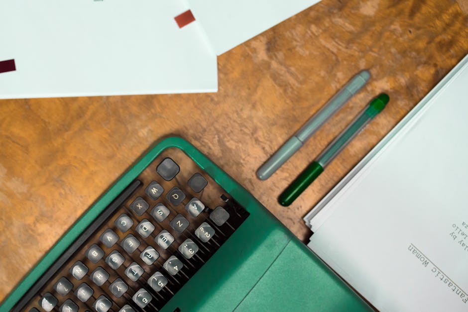 Overhead view of a green vintage typewriter, papers, and pens on a wooden desk, symbolizing professional email writing.
