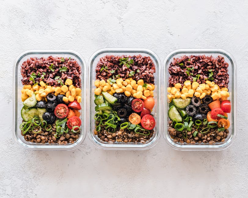 Three healthy weekly meal prep containers with layered rice, corn, olives, cucumber, tomatoes, lentils.