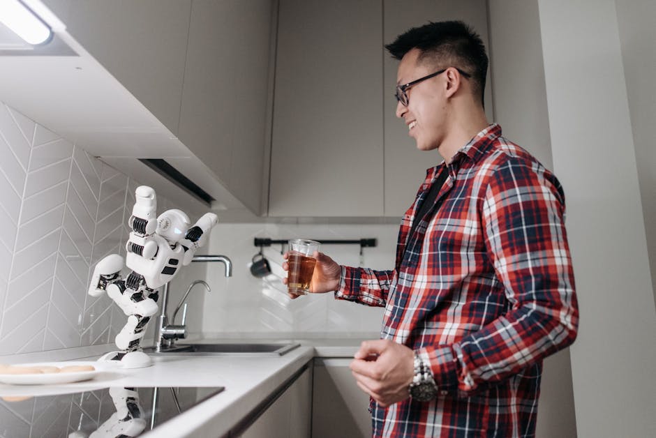 Man smiles at a white AI robot on a modern kitchen counter, showcasing smart kitchen technology and AI assistance.