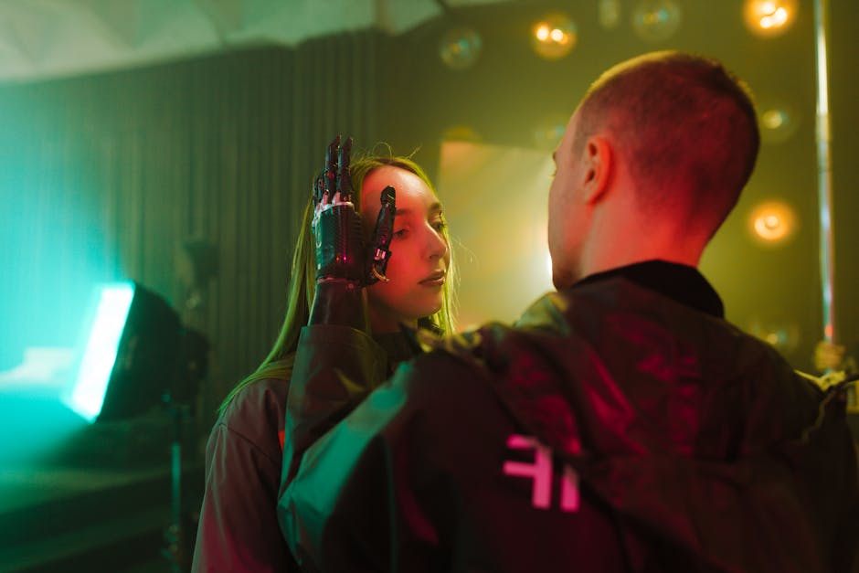 Woman with robotic prosthetic hand on face, interacting with another, in neon-lit scene. Reflects AI influencers and reality.